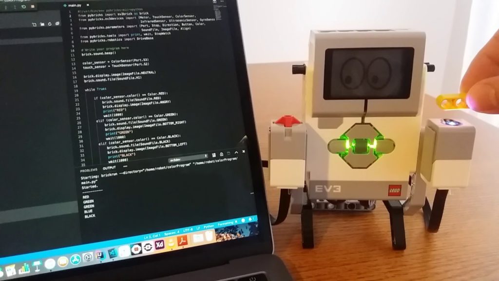 Lego Mindstorms robot next to a computer with code